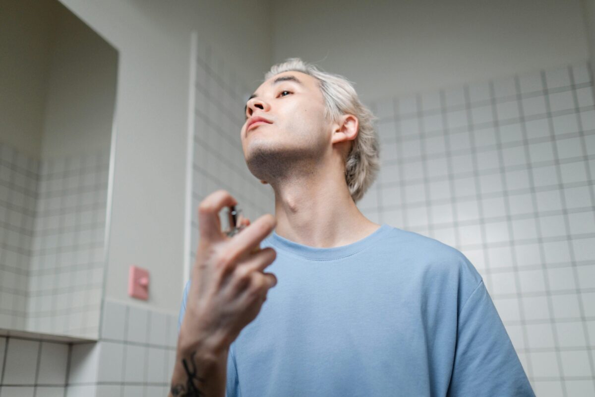 Best Unisex Perfumes 2025: Irresistible Scents in India That Turn Heads Everywhere 7 A stylish young man applying perfume in a contemporary bathroom setting, embracing a metrosexual lifestyle.