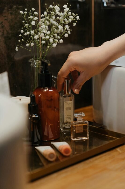 Unlocking the 9 Powerful Secrets Behind the Difference Between Attar and Perfume 13 A serene bathroom scene featuring stylish skincare products and a hand reaching for a perfume bottle.